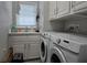 Laundry room with white cabinets, sink, and modern, front loading washing machine and dryer at 530 Walnut Cir, Venice, FL 34285