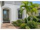 Close up of the front entrance with beautiful landscaping, a gray door, and white exterior at 5665 Piccolo St, Nokomis, FL 34275