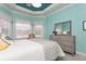 A well-lit bedroom has a large dresser, a tray ceiling and large windows overlooking a garden at 5665 Piccolo St, Nokomis, FL 34275