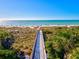 Scenic boardwalk leading to a sandy beach with clear blue ocean water at 605 Cornwell On The Gulf, Venice, FL 34285