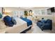Inviting bedroom featuring a plush blue chair, white furnishings, coastal decor, and shuttered windows at 746 Eagle Point Dr, Venice, FL 34285
