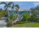 Beautiful coastal home with lush landscaping, a grand staircase, and a calming blue facade at 746 Eagle Point Dr, Venice, FL 34285