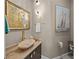 Elegant powder room boasts an oval stone sink, gold fixtures, statement mirror, and nautical artwork at 746 Eagle Point Dr, Venice, FL 34285