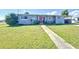 Inviting single-story home featuring a lush lawn, sidewalk, and an eye-catching red front door at 7903 Hyde Park Ave, North Port, FL 34287
