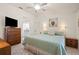 Comfortable main bedroom with tile floors, ceiling fan, dresser, and ensuite bathroom at 888 Guild Dr, Venice, FL 34285