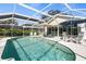 Inviting screened-in pool area featuring a sparkling pool, sun umbrellas, and outdoor furniture at 888 Guild Dr, Venice, FL 34285