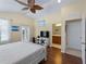 Bright main bedroom featuring a ceiling fan, wood floors, an ensuite bathroom, and a private balcony at 12468 Shimmering Oak Cir, Venice, FL 34293
