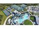 Aerial view of a community pool, tennis courts, pickleball courts, and parking lot at 12580 Galapagos Ct # 107, Venice, FL 34293