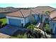 Beautiful single-story home featuring a gray garage door, tile roof, and tropical landscaping at 12744 Oriago St, Venice, FL 34293