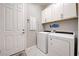 The laundry room has a washer, dryer, and overhead storage cabinets at 12744 Oriago St, Venice, FL 34293