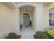 Inviting front entrance with a light-yellow facade, arched doorway, and tiled floor at 1298 Highland Greens Dr, Venice, FL 34285