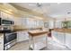 Bright kitchen with white cabinets, granite countertops, stainless steel appliances, and a portable wooden island at 1298 Highland Greens Dr, Venice, FL 34285