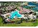 Aerial view of a resort style pool with many chairs, umbrellas and a beautiful clubhouse at 13238 Famiglia Dr, Venice, FL 34293