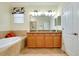 Bathroom featuring double sinks with granite counters, a soaking tub, and tiled flooring at 13238 Famiglia Dr, Venice, FL 34293