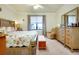Bright bedroom showcasing a floral bedspread, light wood furniture, and a view of the lake at 13238 Famiglia Dr, Venice, FL 34293