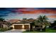 Charming home featuring a two-car garage, stone accents, tile roof, and a lush green lawn at 13238 Famiglia Dr, Venice, FL 34293