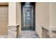 The front door features decorative glass and a secure screen, framed by stone pillars and a brick walkway at 13238 Famiglia Dr, Venice, FL 34293