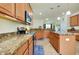 Bright kitchen featuring granite countertops, wooden cabinets, and modern stainless steel appliances at 13238 Famiglia Dr, Venice, FL 34293