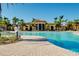 A resort-style pool with a brick paver deck, lush landscaping, and a clubhouse in the background at 13238 Famiglia Dr, Venice, FL 34293