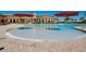 A large community pool with a fountain and umbrellas, surrounded by palm trees and a clubhouse at 13238 Famiglia Dr, Venice, FL 34293