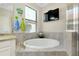 Bright bathroom featuring a soaking tub, glass enclosed shower, granite countertops, and a wall-mounted TV at 13730 Vancanza, Venice, FL 34293