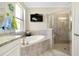 Bright bathroom featuring a soaking tub, glass enclosed shower, granite countertops, and a wall-mounted TV at 13730 Vancanza, Venice, FL 34293