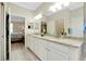 Bright bathroom featuring dual sinks, granite countertops, a walk-in shower, and an adjacent bedroom at 13730 Vancanza, Venice, FL 34293