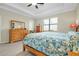 Spacious bedroom featuring light colored laminate flooring, ceiling fan and a large window at 13730 Vancanza, Venice, FL 34293