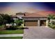 Beautiful home featuring a paver driveway, three car garage, and lush landscaping at 13730 Vancanza, Venice, FL 34293