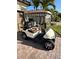 Tan golf cart featuring comfortable patterned seats and chrome wheels parked on a brick driveway at 13730 Vancanza, Venice, FL 34293