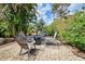 Lush backyard with tropical landscaping, gravel, pavers, and a cozy seating area with a fire pit at 1700 Manasota Beach Rd, Englewood, FL 34223