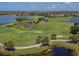 An aerial view of a lush golf course with players enjoying a sunny day surrounded by lakes and trees at 190 Montelluna Dr # North, North Venice, FL 34275