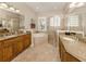 Bright main bathroom with dual vanities, a soaking tub, a glass-enclosed shower, and natural light at 190 Montelluna Dr # North, North Venice, FL 34275