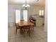 Bright dining area with a wooden table, chairs, and a modern chandelier adjacent to the kitchen with a breakfast bar at 2863 Twinkle Ave, North Port, FL 34286