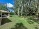 A view of the backyard showing a home with a screened-in lanai and a lush perimeter of trees at 3348 Trapper Ln, North Port, FL 34286