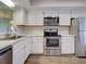 Modern kitchen featuring white cabinets, stainless steel appliances, marble countertops, and stylish wood-look flooring at 345 Three Lakes Ln # L, Venice, FL 34285