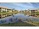Scenic waterfront community with a serene pond reflecting the surrounding buildings, trees, and clear blue sky at 345 Three Lakes Ln # L, Venice, FL 34285