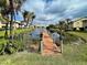 A community pond features a wooden dock, tranquil water, and palm trees providing an idyllic waterfront setting at 345 Three Lakes Ln # L, Venice, FL 34285