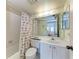 Well-lit bathroom with white tile, vanity, and seashell themed shower curtain and decor at 630 Bird Bay E Dr # 208, Venice, FL 34285
