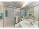 Well-lit bathroom with a glass-enclosed shower, white tile, and a large vanity mirror at 630 Bird Bay E Dr # 208, Venice, FL 34285