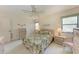 Comfortable bedroom with tropical bedspread, ceiling fan, and natural light from the large window at 630 Bird Bay E Dr # 208, Venice, FL 34285
