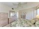 Comfortable bedroom with tropical bedspread, ceiling fan, and natural light from the large window at 630 Bird Bay E Dr # 208, Venice, FL 34285