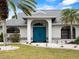 Front entry featuring a blue double-door, walkway, and manicured landscape with mature palm trees at 8 Bunker Ln, Rotonda West, FL 33947