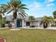 Well-maintained front yard with lush grass, palm trees, blue front door, and manicured landscaping at 8 Bunker Ln, Rotonda West, FL 33947