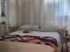 Bright bedroom featuring a comfortable bed with a colorful quilt and natural light streaming through sheer curtains at 88 Bainbridge Dr # 88, Nokomis, FL 34275