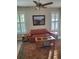 Living area with wood plank floors, orange sofa, and two windows with wood shutters at 1115 Gladstone Blvd, Englewood, FL 34223