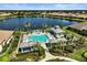 Aerial view of community pool, cabana, and spa with views of the lake and manicured landscaping at 11644 Okaloosa Dr, Venice, FL 34293