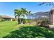 Manicured backyard featuring lush lawn, tropical plants, and screened-in pool enclosure at 13240 Amerigo Ln, Venice, FL 34293