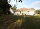 Exterior rear view showcasing an open backyard with green lawn, a patio and natural landscaping at 157 Algiers Dr, Venice, FL 34293