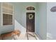 Close-up of the front door adorned with a floral wreath, complemented by a bench and window with shutters at 1610 Monarch Dr # 1610, Venice, FL 34293
